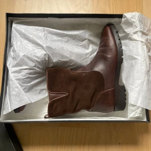 Bruna boots - Snygga bruna boots från Massimo Dutti i en mix av skinn och mocka. De har rund tå, grov sula och är fodrade med mjukt foder för extra värme. Perfekta för kyliga dagar och har en klassisk, stilren look med diskreta detaljer.
