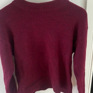 Vinröd stickad tröja från Stories XS - Mysig vinröd stickad tröja från Stories i storlek XS. Tröjan har en enkel design med rund hals och långa ärmar, perfekt för dig som gillar klassiska och stilrena plagg. Materialet är mjukt och skönt, och färgen är djup vinröd.