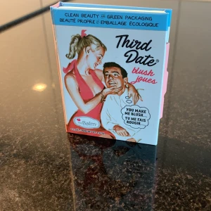 theBalm Third Date blush - Säljer theBalm Third Date blush i en snygg retro-inspirerad förpackning. Rouget har en varm, rosabrun nyans med lätt skimmer och kommer i en pappkartong med spexig design. Perfekt för att ge kinderna en fräsch glow och färg.