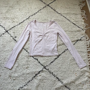 Ljusrosa långärmad topp med rynk - Supersöt ljusrosa långärmad topp med v-ringning och snygg rynkdetalj framtill. Modellen är figurnära och i mjuk bomullskvalitet, perfekt till jeans eller kjol. Enkel och stilren design som är lätt att matcha. Defekter finns! Se alla dom tre sista bilderna!🥰❤️