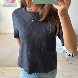 Mörkgrå stickad topp från Zara - Mörkgrå stickad topp från Zara med rund halsringning och halvkort ärm. Toppen har en rak passform och dragkedja bak i nacken. Storlek L men sitter mer som S/M.