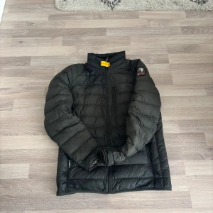 Svart dunjacka från Parajumpers - Säljer en svart dunjacka från Parajumpers med klassisk patch på ärmen och gul detalj vid kragen. Jackan är superlätt, har dragkedja framtill och flera fickor. Perfekt för kalla dagar och riktigt snygg till streetwear-stilen.