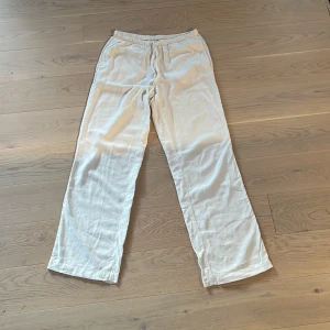 Vita linnebyxor från bikbok  - Säljer ett par stilrena vita linnebyxor med rak passform samt med resår och snöre i midjan. Byxorna är i storlek S. De har använts några gånger, max 10, men de ör vi bra skick. 