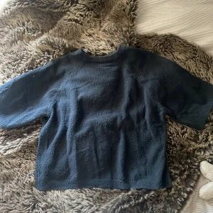 Mörkblå stickad tröja från 157 - Mysig mörkblå stickad tröja från 157 med rund hals och korta ärmar. Perfekt för dig som gillar enkel och chill stil. Materialet är stickat och känns skönt mot huden. Passar dig som vill ha en basic men ändå snygg tröja.