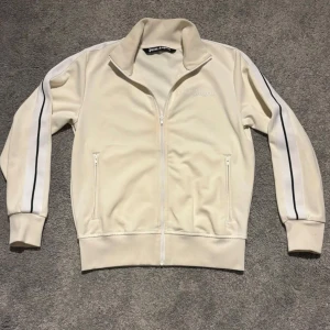 Beige zip hoodie från Palm Angels - Palm Angels beige hoodie med hel dragkedja och ståkrage.  Den är i bra kvalite men täcken på användning, köpt för runt 1500 begagnat, storleken är M men skulle nog säga den passar nån som e mellan 170/185, säljer då den har blivit för liten för mig, den är äkta såklart, dock har jag inget kvitto kvar (förra ägaren hade). Enbart ett par små fläckar på tröjan som inte är jätte synliga,  skriv om ni har frågor, billigare vid snabb affär. 