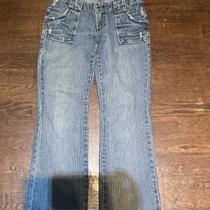 Blå jeans med stora fickor från United - Snygga blå jeans från United med breda ben och stora fickor både fram och bak. Jeansen har en klassisk denimlook med ljusa slitningar och markerade sömmar. Perfekta för dig som gillar en avslappnad och trendig stil.