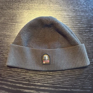 Mörk grön ribbad mössa från Parajumpers - Snygg grå mössa från Parajumpers med ribbad kant och klassisk logopatch framtill. Perfekt för kalla dagar och enkel att matcha med din jacka. Mjuk och skön stickad kvalitet som håller dig varm hela vintern.