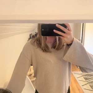 Beige långärmad tröja med vida ärmar - Säljer en beige långärmad tröja med riktigt schyssta vida ärmar och rak passform. Tröjan har en enkel rund halsringning och är gjord i ett mjukt material som känns skönt mot huden. Perfekt för dig som gillar stilrena och chill plagg.
