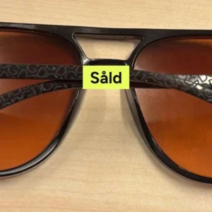 Svarta pilotglasögon med mönstrade skalmar - Snygga pilotglasögon med svarta bågar och bruna glas. Skalmarna har ett diskret mönster som ger extra stilpoäng. Perfekt för dig som vill sticka ut med en klassisk men cool look.