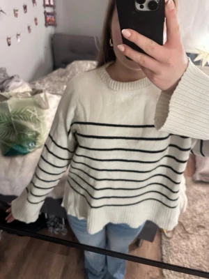 Vit randig stickad tröja lager157  - Säljer en vit stickad tröja från lager 157 i storlek M. Tröjan har svarta horisontella ränder, rund hals och breda ribbade muddar vid ärmslut och nederkant. Modellen är loose fit och har långärmade ärmar, perfekt för chilliga dagar.