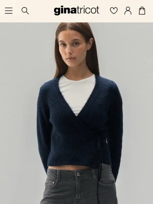 Mörkblå omlottkofta från Gina Tricot - Säljer en helt ny mörkblå omlottkofta från Gina Tricot med prislapp kvar. Koftan har knyt i sidan, v-ringning och är stickad i ett mjukt material. Perfekt att styla med jeans eller kjol för en chill look. Pris kan diskuteras. Skickar snabbt.