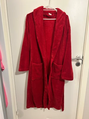 Röd morgonrock från Biltema S/M - Mysig röd badrock från Biltema i storlek S/M. Har mjukt material med två stora fickor och ett bälte i midjan. Funkar även som badrock. Helt oanvänd
