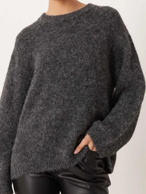 Mörkgrå stickad tröja - Mysig och fluffig mörkgrå stickad tröja med rund hals och långa ärmar. Perfekt för kyliga dagar och enkel att matcha med både jeans och skinnbyxor. Tröjan har en loose passform som ger en avslappnad vibe.