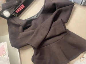 Svart peplum topp från Monki - Säljer en svart peplum topp från Monki med lång ärm och rundad hals. Toppen har en markerad midja och volang nedtill som ger en snygg siluett. Materialet känns mjukt och stretchigt, perfekt att styla med jeans eller kjol.