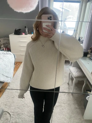 Beige stickad tröja med hög krage - Säljer en beige stickad tröja med hög krage och långa ärmar. 