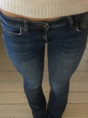 Blå bootcut jeans från Zara, strl 34 - Snygga blå jeans från Zara i storlek 34 med klassisk bootcut-passform och låg midja. Jeansen har en mörk tvätt och är tillverkade i jeansmaterial med stretch. Perfekta för dig som gillar en retro vibe och vill ha ett par jeans med lite utsvängda ben. Sänkt priset idag!🥰