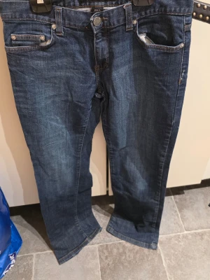 Mörkblå jeans från Calvin Klein Jeans - Snygga mörkblå jeans från Calvin Klein Jeans med klassisk femficksdesign och raka ben. Jeansen har en stilren look med kontrastsömmar och metallknapp med logga. Tillverkade i slitstarkt denimtyg som ger en tidlös vibe.