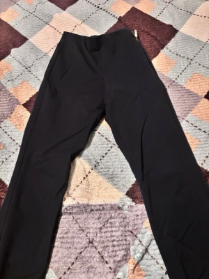 Mörkblå kostymbyxor Holly & Whyte - Mörkblå kostymbyxor från Holly & Whyte by Lindex i storlek 36. Byxorna har en klassisk rak passform med midwaist och är tillverkade i ett mjukt bomullsmaterial. De stängs med guldfärgad dragkedja och knapp i midjan. Perfekta för en clean och stilren look.