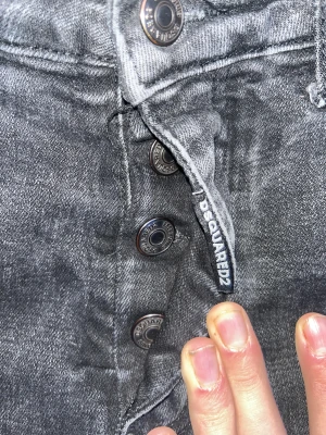 Svarta jeans från Dsquared2 kom med bud - Säljer ett par svarta skinny jeans från Dsquared2 med slitningar och distressed detaljer. Jeansen har knappar med Dsquared2-logga, klassisk femficksmodell och en snygg tvättad look. Perfekta för dig som gillar streetstyle och vill sticka ut.