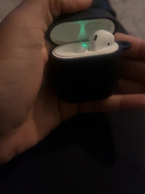 Apple AirPods (2nd generation) - Säljer ett par Apple AirPods (2nd gen) med laddningsetui. Hörlurarna är trådlösa och fungerar utmärkt, med synlig grön indikatorlampa. Skicket är gott, endast mindre yttre slitage på etuiet. Perfekt för musik, samtal och träning.