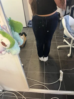 Mörkblå mjukisbyxor Juicy Couture M - Säljer ett par mörkblå mjukisbyxor från Juicy Couture i storlek M. Byxorna har snörning i midjan och raka ben, med klassiska fickor bak och fram. Materialet är mjukt och skönt, perfekt för chill dagar. Snygg och enkel design med diskret logga. Saknas en metall del