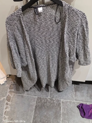 Gråmelerad kofta från H&M Divided - Säljer en chill och mjuk gråmelerad kofta från H&M Divided i storlek S. Koftan har ett grovstickat mönster, öppet framtill och avslappnad passform med långa ärmar. Perfekt att slänga på sig när det är lite kyligt ute.