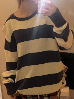 Randig stickad tröja Brandy Melville - Säljer en oversized stickad tröja från Brandy Melville med breda mörkblå och vita ränder. Tröjan har rund hals, långa ärmar och ribbade muddar vid hals, ärmslut och nederkant. Perfekt för chill dagar och enkel att styla med jeans eller leggings.
