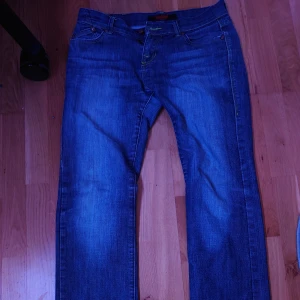 Jeans från Lee Cooper - Säljer ett par klassiska blå jeans från Lee Cooper. Raka ben, gul kontrastsöm och knappstängning fram. Perfekt för dig som gillar enkel och tidlös stil. Materialet är slitstarkt jeans.