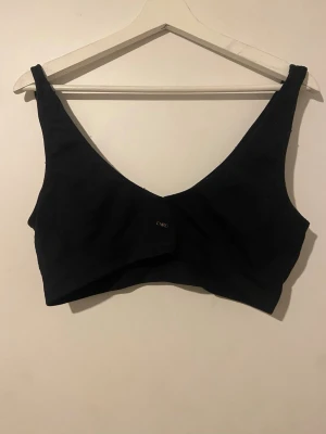 Svart sport BH - Säljer en svart  låg- till medelstöd sport-BH med djup v-ringning och breda axelband med ett stretchig material. . Passar dig som vanligtvis har S eller M även L. 