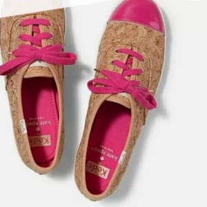 KEDS x Kate Spade Corkie Lipstick Pink Natural Cork Sneaker - Unika sneakers med korkmönstrad ovandel, rosa snörning och glansig rosa tå. Insidan är rosa och sulan har en vit bas med rosa rand. 