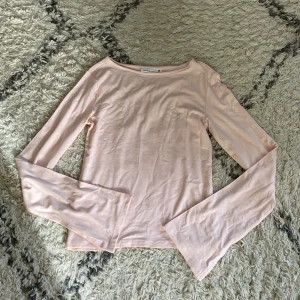 Ljusrosa långärmad topp från Gina Tricot - En enkel och stilren ljusrosa långärmad topp från Gina Tricot. Toppen har rund halsringning och är tillverkad i mjuk bomull, perfekt för lager-på-lager eller som den är. Passformen är normal och tyget är tunt och skönt.