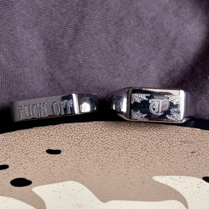 Två sterling silver ringar med gravyr - Säljer två ringar i sterlingsilver . Ena ringen har texten 'FUCK OFF' ingraverad och den andra har ett dekorativt mönster med bokstaven T i mitten. Perfekt för dig som gillar att sticka ut med dina accessoarer. 80kr styck!