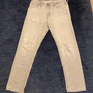 Grå jack and jones jeans - Snygga grå jeansbyxor. Byxorna har normal passform och är tillverkade i slitstarkt jeanstyg. Perfekta för dig som gillar en enkel och stilren look.