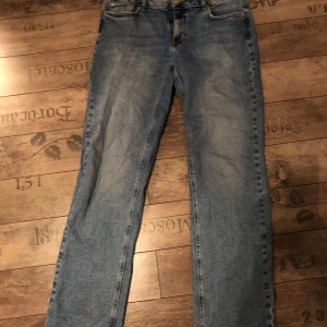 Blå jeans från NA-KD med råa kanter - Säljer ett par klassiska blå jeans från NA-KD med raka ben och slitna benslut. Otroligt stretchiga och bekväma jeans. Perfekta för en avslappnad och trendig look.