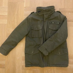 Grön parkajacka Zadig & Voltaire - Snygg militärgrön parkajacka från Zadig & Voltaire med broderad färgglad vinge och texten 'Rock & Roll' på ryggen. Jackan har hög krage, fyra fickor framtill och coola axeldetaljer. Perfekt inför hösten!!!! 