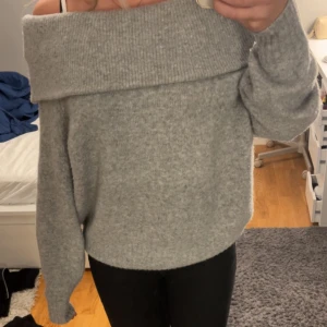Grå offshoulder stickad tröja - Supermysig grå stickad tröja från H&M i offshoulder-modell. Perfekt för kyliga dagar nu i höst och i vinter och enkel att styla med jeans eller kjol.Använt 2 gånger