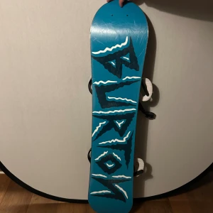 Burton Chopper 120 Snowboard - Ny pris 3000kr.                                        Burton Chopper 120 snowboard med cool grafisk design och svarta bindningar. Brädan är i gott skick med endast mindre ytliga repor, perfekt för juniorer eller nybörjare. Bindningarna är hela och funktionella. Snygg färg och pålitlig kvalitet från Burton.