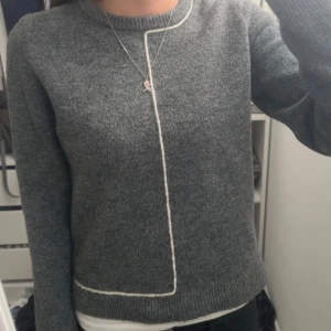 Grå stickad tröja med vit kant - Pris går att diskutera!!!!!!!Snygg grå stickad tröja med lång ärm och en vit kant som går längs halsen och ner på framsidan. Tröjan har en rund halsringning och är perfekt för dig som gillar enkel men cool design. Passar till jeans eller kjol för en chill look. Strl m men är väldigt liten i storlek passar som xs