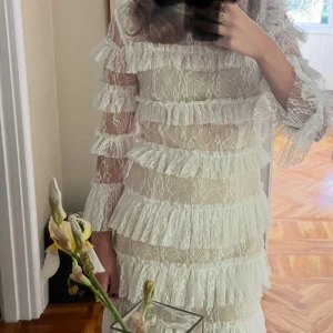 Vit spetsklänning med volanger från By malina - Sååå fin vit klänning med flera lager volanger och spetsdetaljer. Klänningen har trekvartsärmar i spets och en figurnära passform. Från By Malina 😍😍😍