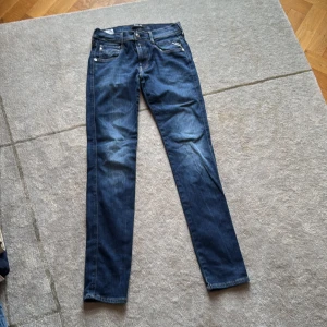 Replay Anbass slim jeans blå - Snygga blå jeans från Replay, modell Anbass. Slim fit med klassisk femficksdesign, ljusa kontrastsömmar och detaljerade bakfickor. Jeansen har normal midja och är tillverkade i mjukt denim med lite stretch för extra komfort.