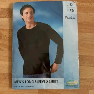 Ny, grå långärmad tröja från PowerLine - Säljer en grå långärmad tröja från PowerLine med v-ringad hals och små svarta broderade symboler på bröstet. Tröjan är tillverkad av 85% bomull och 15% viskos, vilket gör den mjuk och skön. Perfekt för dig som gillar enkel och stilren design.