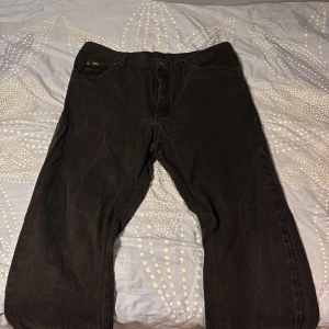 Svarta Lee jeans straight fit - Svarta jeans från Lee med klassisk femficksdesign och rak passform. Jeansen har Lee-logga på bakfickan och är tillverkade i ett robust jeanstyg. Perfekta för dig som gillar en tidlös och enkel stil.