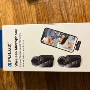 Puluz Wireless Microphone - Trådlöst lavaliermikrofonsystem från Puluz med två mikrofoner och en mottagare. Perfekt för intervjuer, vloggning och videoinspelning med smartphone. Produkten är ny i förpackning och passar både iOS och Android-enheter.