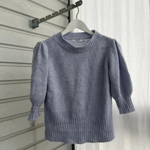 Ljuslila stickad tröja från NA-KD - Superfin ljuslila stickad tröja från NA-KD med puffärmar och bred ribbad mudd vid ärmslut och nederkant. Tröjan har rund halsringning och en mjuk, mysig känsla – perfekt för lager på lager under kyliga dagar.