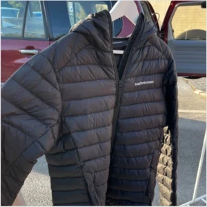 Svart dunjacka Peak Performance S - Svart dunjacka från Peak Performance i storlek S. Jackan har luva, quiltad design och dragkedja framtill. Perfekt för kyliga dagar och har en clean, sportig look som funkar till det mesta. Den är använd och har små defekter 