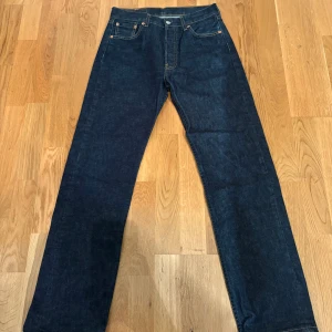 Levi's 501  - Klassiska Levi's 501 jeans i mörkblå denim med raka ben och hög midja. Byxorna har fem fickor, synliga kontrastsömmar och den ikoniska läderpatchen bak i midjan. Perfekta för dig som gillar tidlös stil och schysst passform. Sitter som en 29/32 och inte 30/32