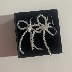 Pärlörhängen från Gina  - Säljer supersöta örhängen med vita pärlor formade som stora rosetter. De har silvriga krokar för enkel användning. Ny utan prislapp. 