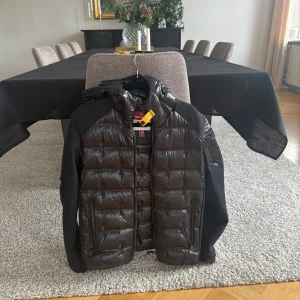 Svart pufferjacka från Parajumpers M - Snygg svart pufferjacka från Parajumpers i modell Piquet Puffers. Jackan har glansig, quiltad framsida och rygg, samt släta svarta ärmar och huva. Dragkedja framtill och två fickor med dragkedja. Köpt på johnells för 4500 och är riktigt enkel till outfits. Fraktas även i tryggt och säkert paket!