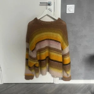 Randig mohairtröja från COS i L - Supermjuk och oversized stickad tröja från COS i storlek L. Tröjan har breda ränder i brunt, gult, beige och rosa och är gjord i mohair- och ullmix.