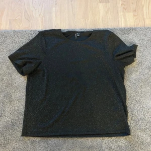 Svart glittrig topp från Vero Moda - Svart glittrig topp från H&M med rund halsringning och korta ärmar.
